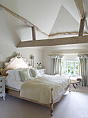 Doppelbett unter hoher Balkendecke in einem Haus in Buckinghamshire, Großbritannien