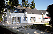 Gekieste Einfahrt vor einem einstöckigen, sonnenbeschienenen Bauernhaus in der Bretagne Frankreich