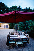 Lit candles on al fresco dining table below parasol at dusk Brittany France