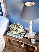 Light blue lampshade and dried flowers on bedside crate in Brittany guesthouse France