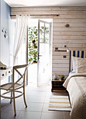 Offene Tür zu einem sonnenbeschienenen Schlafzimmer in einem Gästehaus in der Bretagne, Frankreich