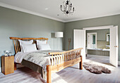 Doppelbett aus Holz in einem hellgrünen Schlafzimmer mit eigenem Bad in einem Herrenhaus in Northumbria (England)