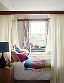 Verschiedene Kissen mit bunter Decke auf einem Himmelbett in einem Herrenhaus in Northumbria, England UK
