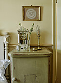 Single stem flowers and clock on bedside cabinet in Whitley Bay cottage Tyne and Wear England UK