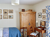 Blue blanket on single bed with wooden wardrobe and antique dressing table and chair in Hexham farmhouse Northumberland UK