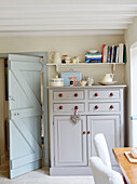 Grau gestrichener Schrank mit Geschirr und Büchern in einem Haus in Northumbria, England, UK