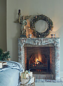 Christmas wreath and statue above lit fire in Oxfordshire bedroom England UK