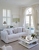 White sofa and square coffee table with arched French doors and shutters in York townhouse England UK