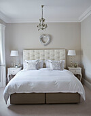 Heart above buttoned headboard with pair of matching lamps in York townhouse England UK