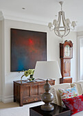 Lamp on side table with modern art canvas above wooden sideboard in modernised Northumbrian country house UK