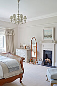 Full length mirror and fireplace with wicker bed in Northumbrian country house UK