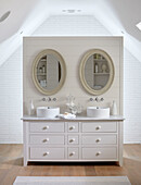 Oval shaped mirrors above double washbasin in modernised Northumbrian country house UK