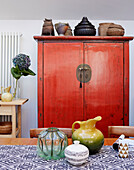 Orientalische Haushaltswaren auf einem roten, chinesisch lackierten Schrank in einem Haus in Speldhurst, Kent, England, UK