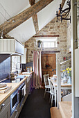 Galley kitchen with exposed stone wall in Grade II listed Tudor bastle or fortified farmhouse Northumberland UK