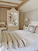 Striped blanket on double bed with mirrored wardrobe in County Durham cottage, England, UK
