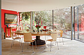 Large circular dining table in glass conservatory extension of 18th century Northumbrian mill house, UK