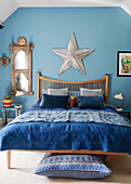 Silver star above wooden bed with blue covers in 18th century Northumbrian mill house, UK