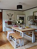 Cut flowers on wooden table with benches with portrait of cow in Kent home, England, UK