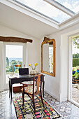 Laptop on desk with vintage chair and gilt framed mirror at window with open door in Yorkshire home, England, UK