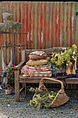 Rusty weathervane and folded blankets on wooden bench in garden exterior of Powys cottage, Wales