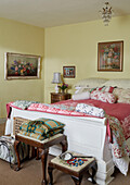 Pink bed cover with patterned cushions in yellow Powys cottage bedroom, Wales, UK