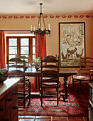 Wooden chairs at table with artwork in Herefordshire farmhouse dining room, UK