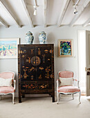 Pair of pink armchairs with Chines lacquered cabinet in Warwickshire farmhouse, UK