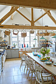 Assorted baskets hang above table in spacious Warwickshire farmhouse kitchen, UK