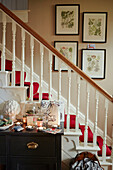 Red carpet on staircase with framed botanical prints in Chippenham home, Wiltshire, UK