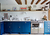 Blaue Einbauschränke mit Regal unter Balkendecke in einem Bauernhaus in Warwickshire, England, UK