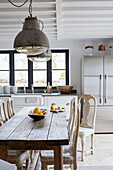 Antique furniture and industrial metal lights in kitchen of renovated Cotswolds cottage, UK
