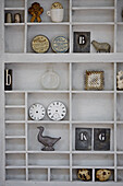 Collection of curios on wall mounted shelving in West Sussex barn conversion, UK