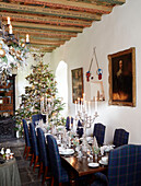 Blue tartan chairs at dining table with Christmas tree in Scottish castle, UK