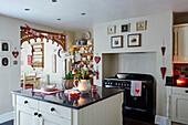 Flowers on island unit with heart decorations and garland at Christmas white fitted kitchen of, UK home