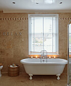 Freistehende Badewanne mit Kerzenlicht am Fenster mit Jalousien und dem Schriftzug 'RELAX' in einem britischen Haus
