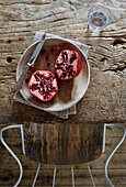 Pomegranate in wooden bowl on table with chair in Camber cottage, East Sussex, UK