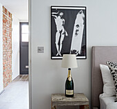 Black and whit print with Champagne bottle lamp at bedside in Rye barn conversion, East Sussex
