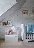 Bücherregal und Kinderbett mit Steppdecke im Kinderzimmer in einem Landhaus in Berkshire, England, UK