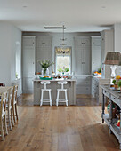 Bar stools at island unit in open plan kitchen of Woodstock home, Oxfordshire, UK