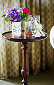 Kingfisher ornament and cut flowers on wooden side table in Syresham home, Northamptonshire, UK