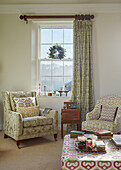 Upholstered armchairs at sash window in Northumberland farmhouse, UK
