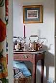 Copper kettles on wooden table with gilt framed artwork in Northumberland farmhouse, UK