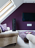 Wall mounted TV and speaker with armchair below skylight in North Yorkshire attic conversion, UK