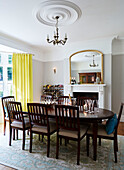 Dining table and chairs with gilt framed mirror and yellow curtains in Durham home, England, UK