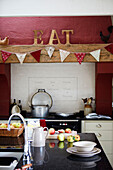 Geschnittene Äpfel auf einer Kücheninsel mit Wimpel über dem Ofen und dem Wort 'EAT' in einer Bauernhausküche in Northumberland, UK