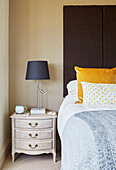 Brown headboard with yellow cushion and grey lamp at bedside in Northumbrian home, UK