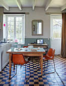 Stühle im Retrostil am Holztisch in der Küche eines bretonischen Landhauses mit gefliestem Boden in Frankreich