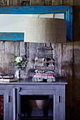 Carved wooden lampbase with hessian shade on purple sideboard in Devon home, UK