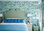 Green and blue bedroom in contrasting patterns with spotted headboard Cotswolds cottage, UK