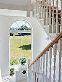 View through arched window to fields from staircase in York home, UK